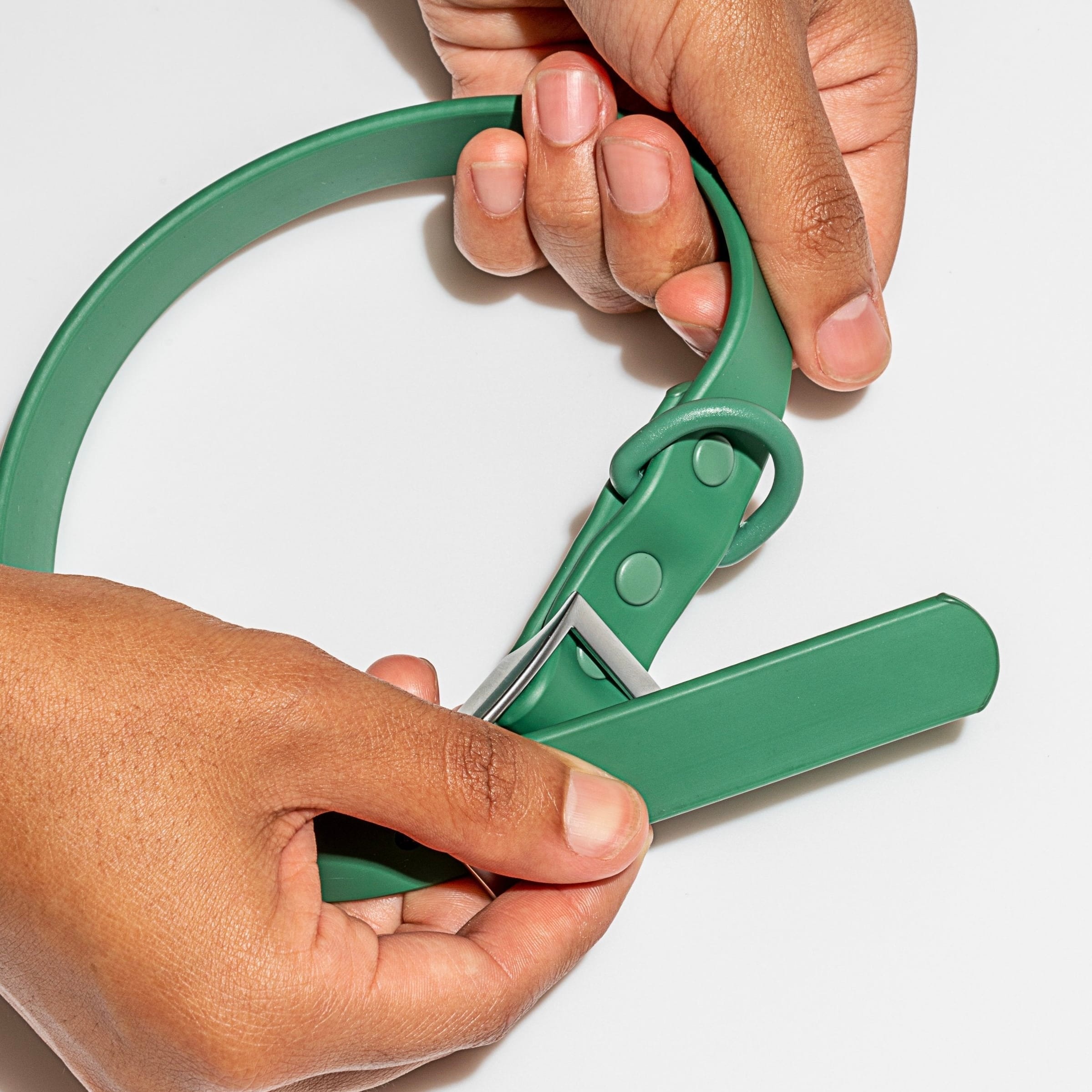 Green waterproof dog collar held in a hand showing buckle and D-ring hardware detail — MoonianPet adjustable collar