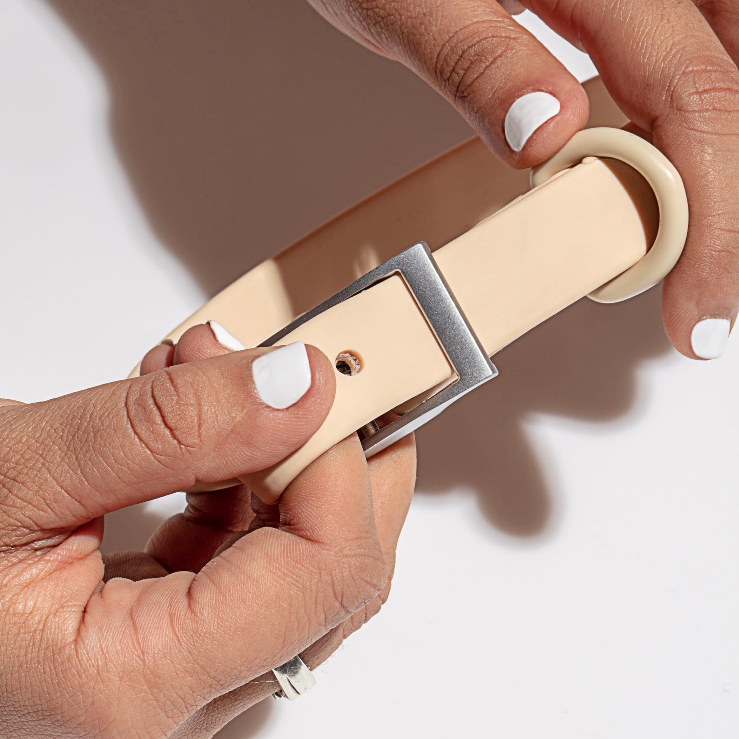 Hand holding a sand coloured waterproof dog collar, showing the smooth, odour-free PVC surface