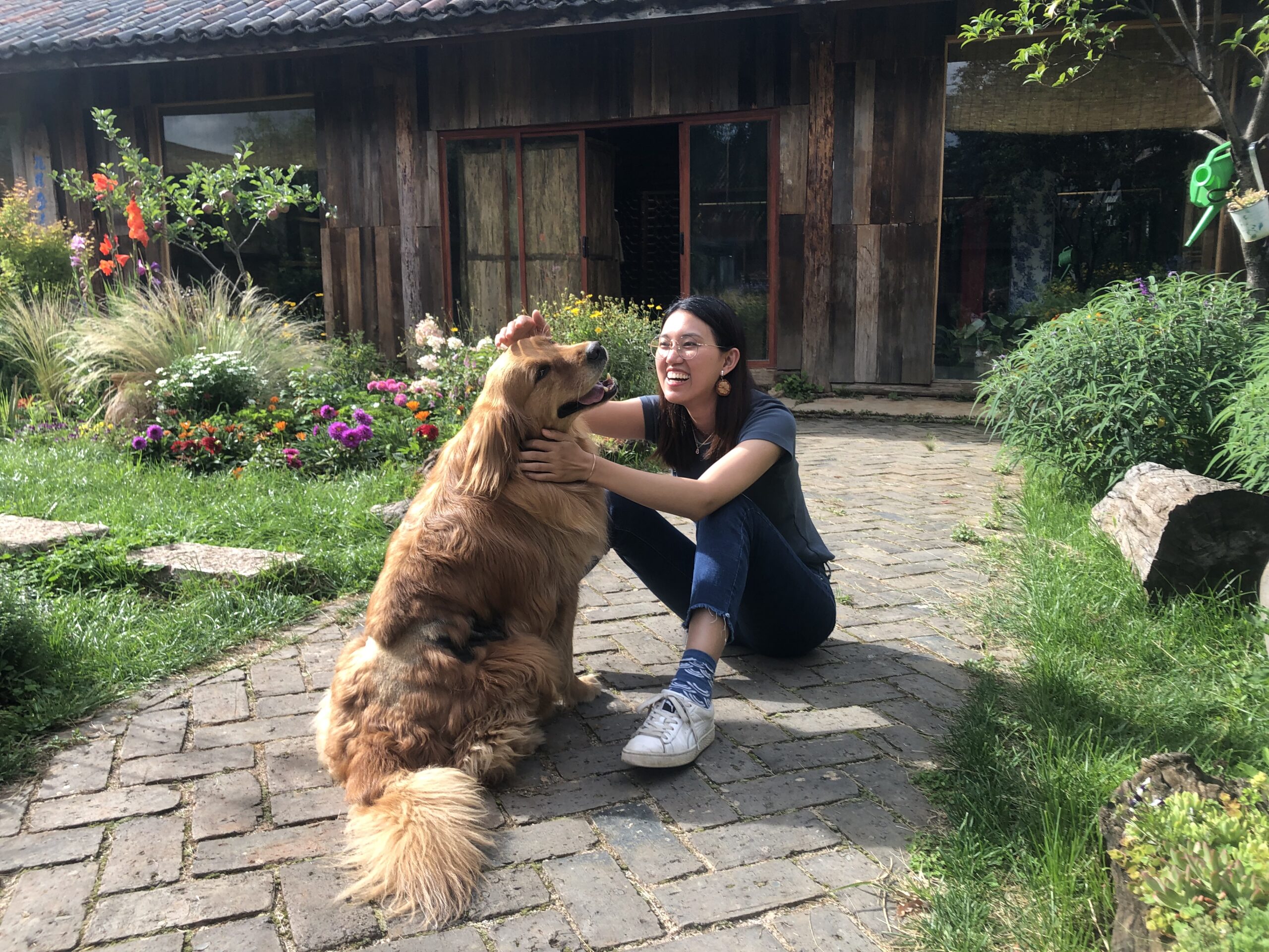Wenyue, founder of MoonianPet, smiling with a Golden Retriever in garden